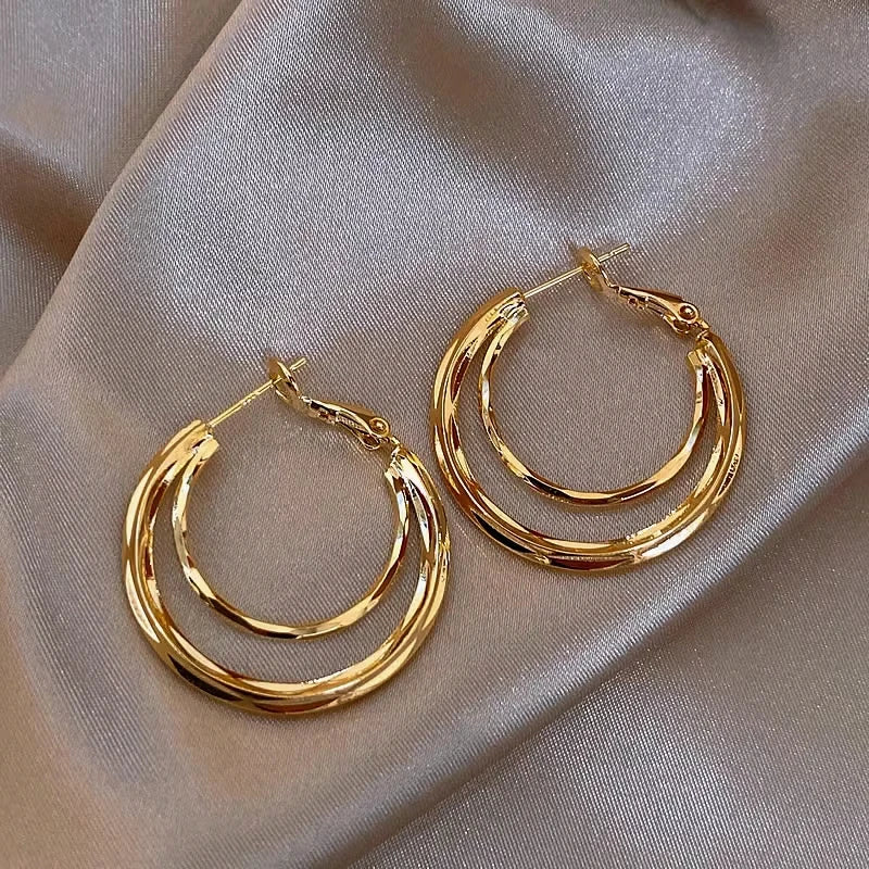 Gold twisted multi-layer hoop earrings on champagne satin fabric