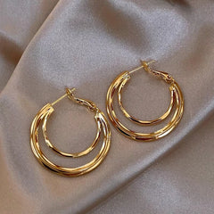 Gold twisted multi-layer hoop earrings on champagne satin fabric