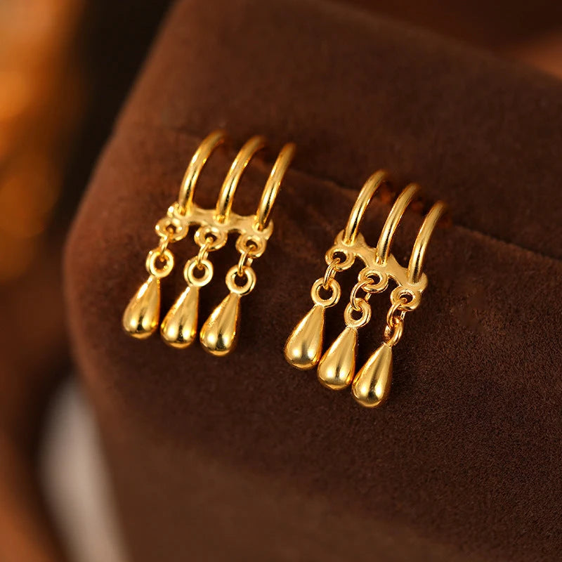 Pair of gold three-row teardrop dangle earrings on velvet display