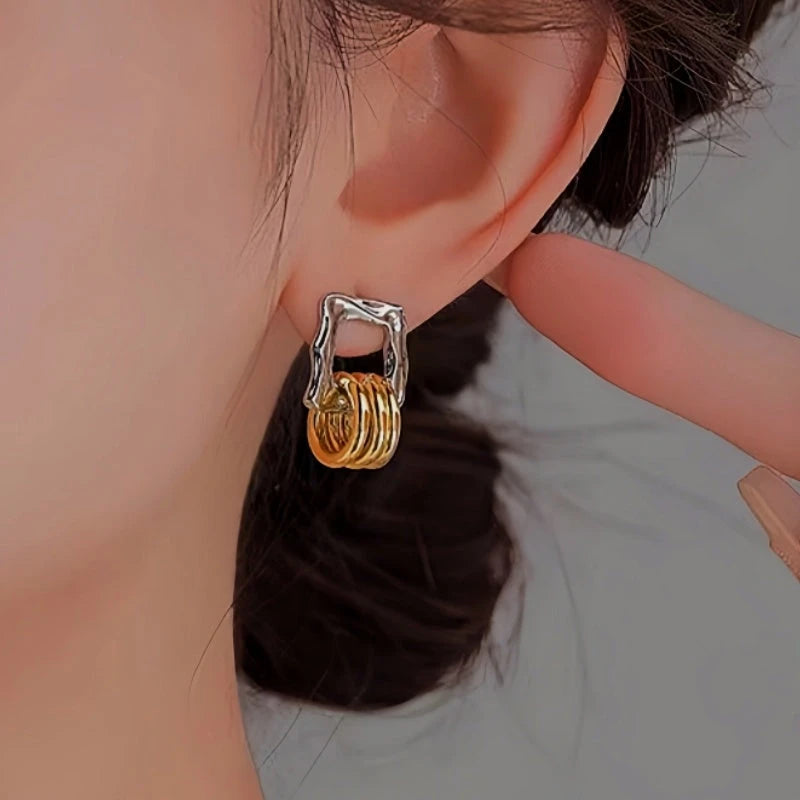 Close-up of silver frame gold layered square hoop earring worn on ear