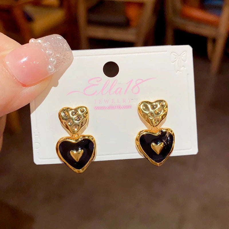 Pair of black enamel gold double heart drop earrings on jewelry display card
