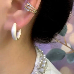White enamel huggie hoop earring and crystal ear cuff on left ear