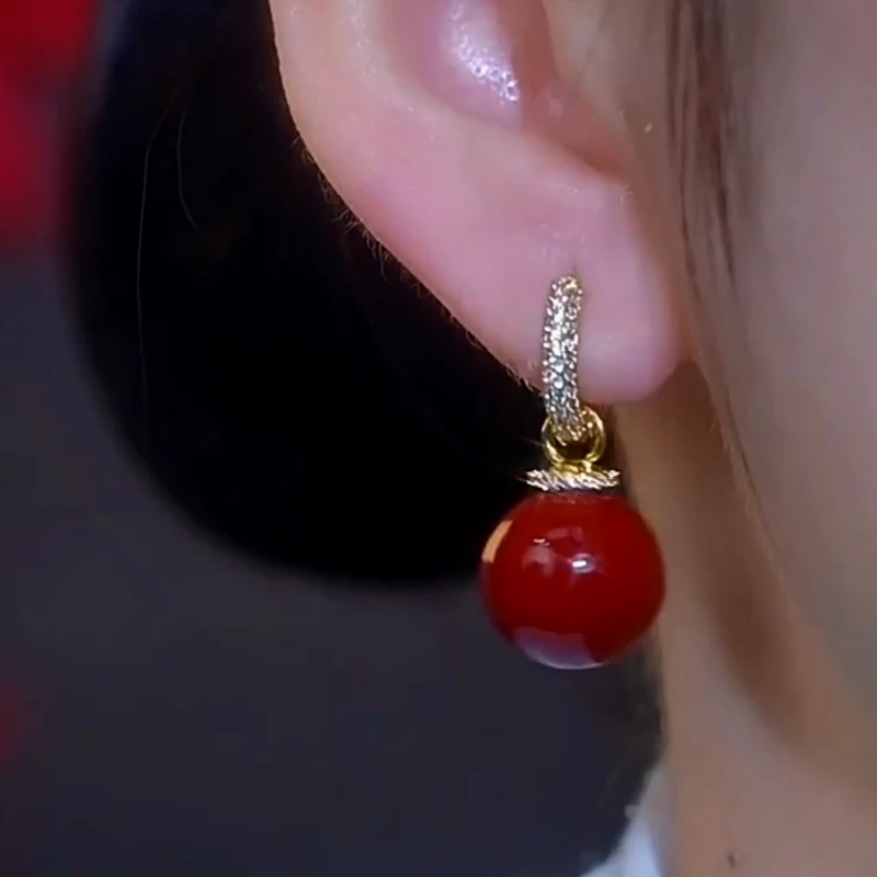 Red bead crystal pave drop hoop earring worn on a person's earlobe