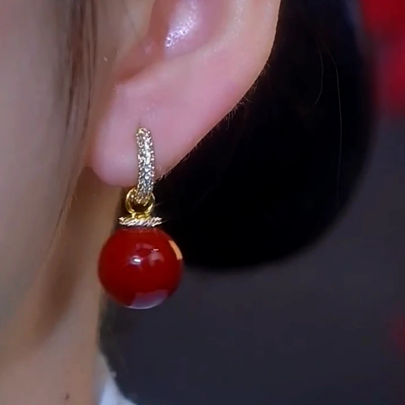Close-up of red bead drop hoop earring with crystal pave on ear