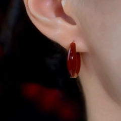 Glossy deep red enamel huggie hoop earring alternate wear view close-up
