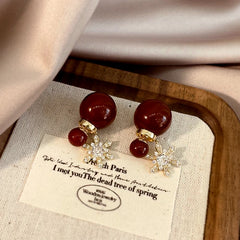 Pair of burgundy bead crystal snowflake dangle earrings, product display on linen tray
