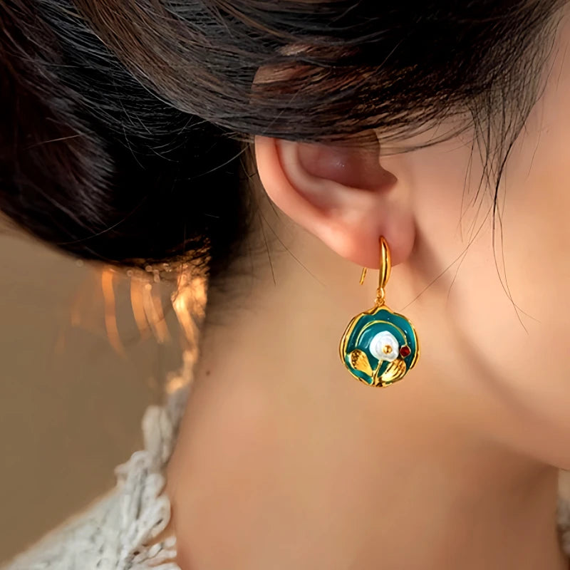 Close-up of teal enamel gold flower drop earring worn on woman's ear