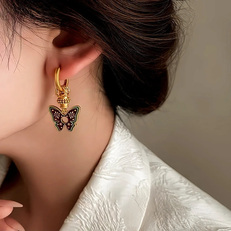 Close up of retro gold butterfly dangle hoop earring worn on ear