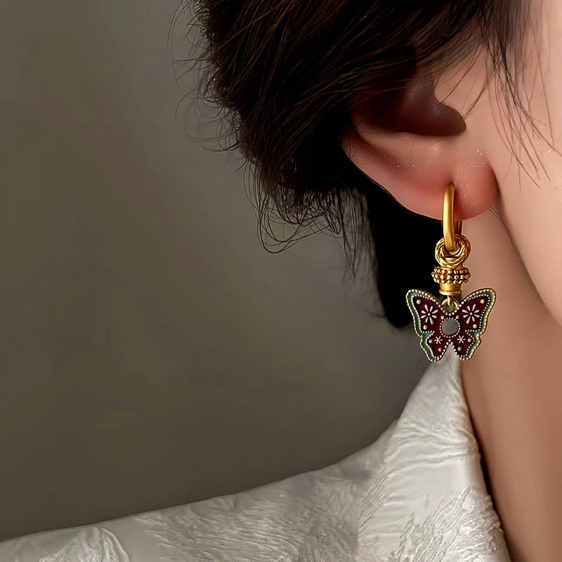 Detailed side view of gold enamel butterfly drop hoop earring on ear