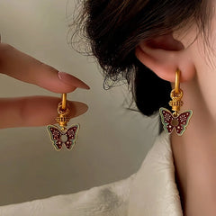 Vintage gold red enamel butterfly drop hoop earrings, hand held beside worn earring