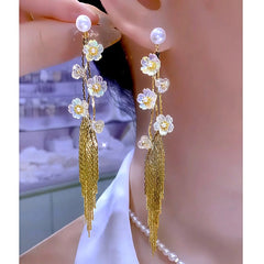 Iridescent floral gold tassel pearl dangle earrings, one worn one held close up