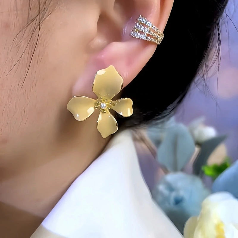 Women's yellow enamel flower pearl stud earring worn on earlobe, close up