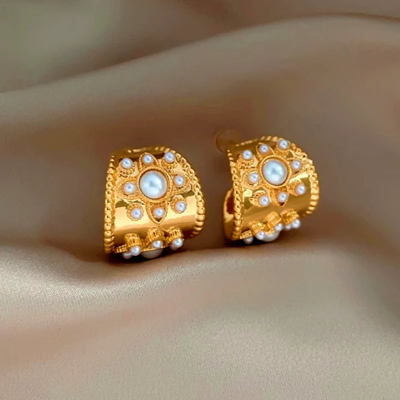 Vintage gold floral pearl wide hoop earrings on beige satin background