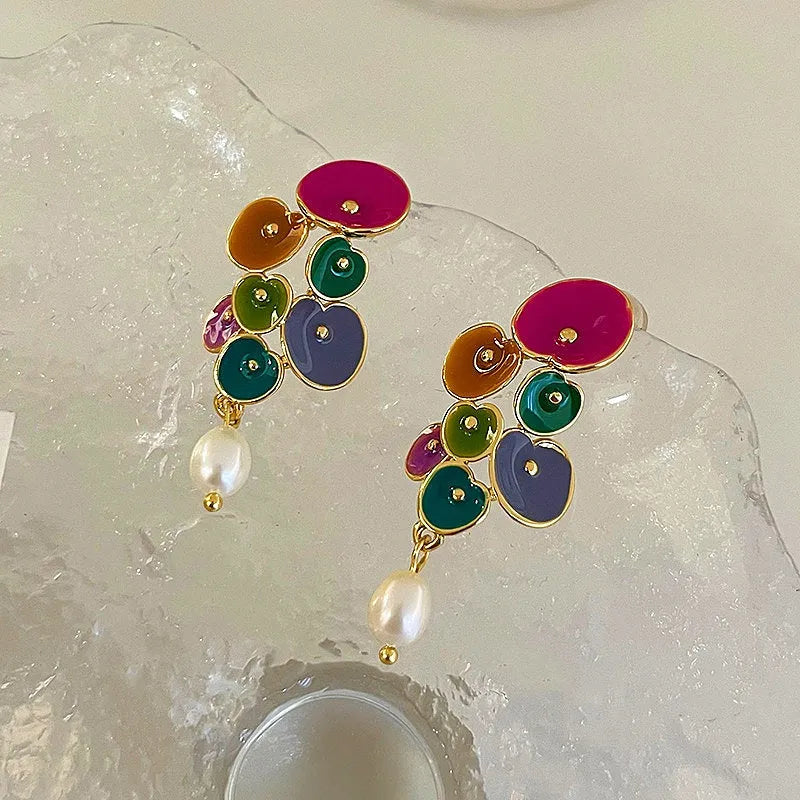 Pair of colorful enamel flower cluster pearl drop earrings on frosted display