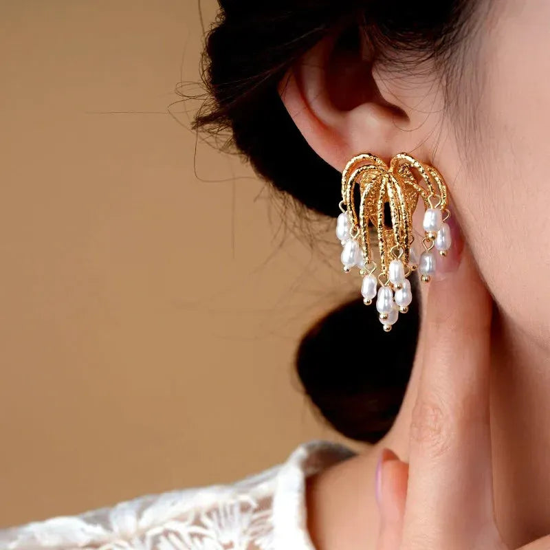 Close up of gold pearl chandelier drop earring worn on woman's ear