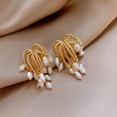 Pair of textured gold pearl drop chandelier earrings on beige satin fabric