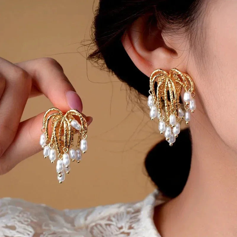 Statement vintage gold pearl chandelier earrings: one worn on ear, one held in hand