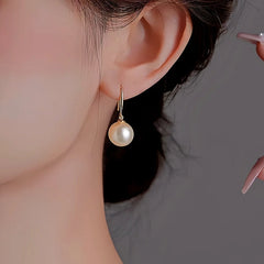Model showcasing the dangle and style of the 14K Gold-Plated Pearl Pendant Earrings