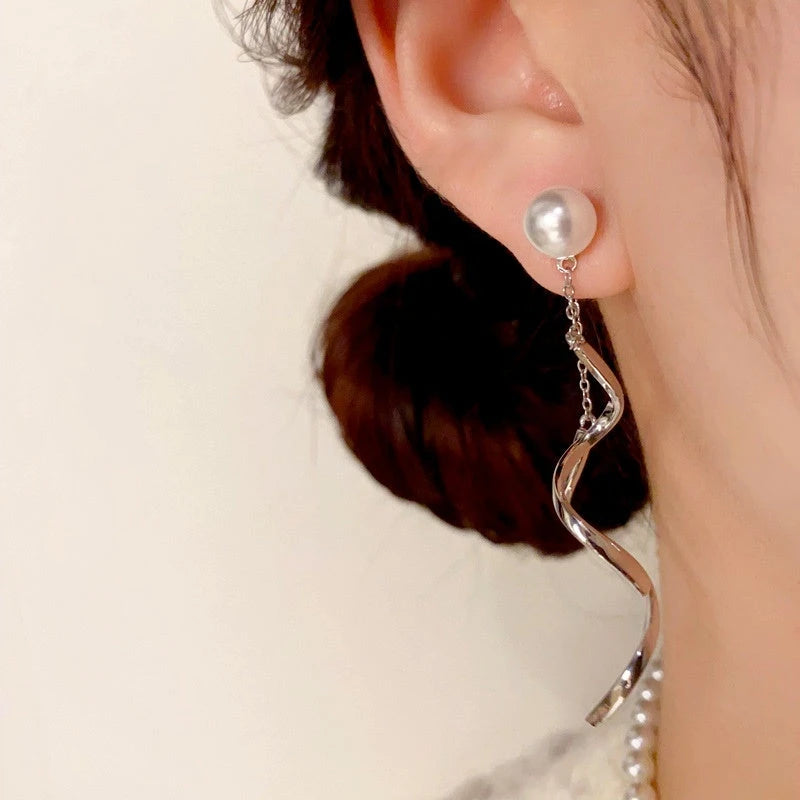 Model showcasing the dangle and style of the 14K Gold-Plated Pearl Spiral Tassel Earrings