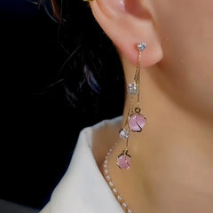 Model showcasing the dangle and style of the 14K Gold-Plated Pink Cat's Eye Ball Tassel Earrings