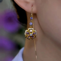 Angled view of gold purple crystal floral long tassel drop earring on ear