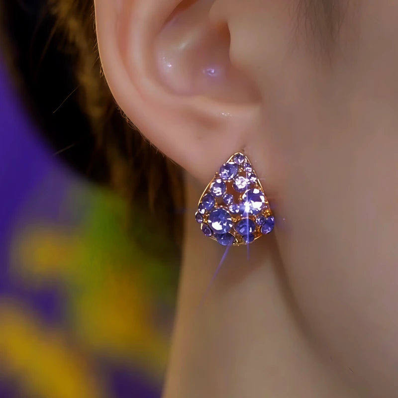 Purple crystal gold triangle stud earring on female ear, close-up side view