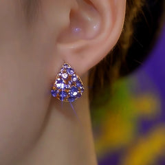 Purple rhinestone gold triangular stud earring worn on woman's earlobe