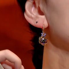 Close-up of Hollow Gold Purple Rose Dangle Earring on Female Ear