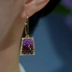 Gold gradient purple-brown crystal trapezoid drop earring worn on ear close-up
