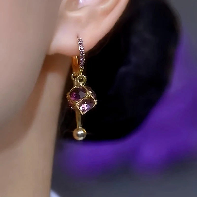 Gold purple cubic crystal dangle huggie hoop earring worn on ear, alternate side view