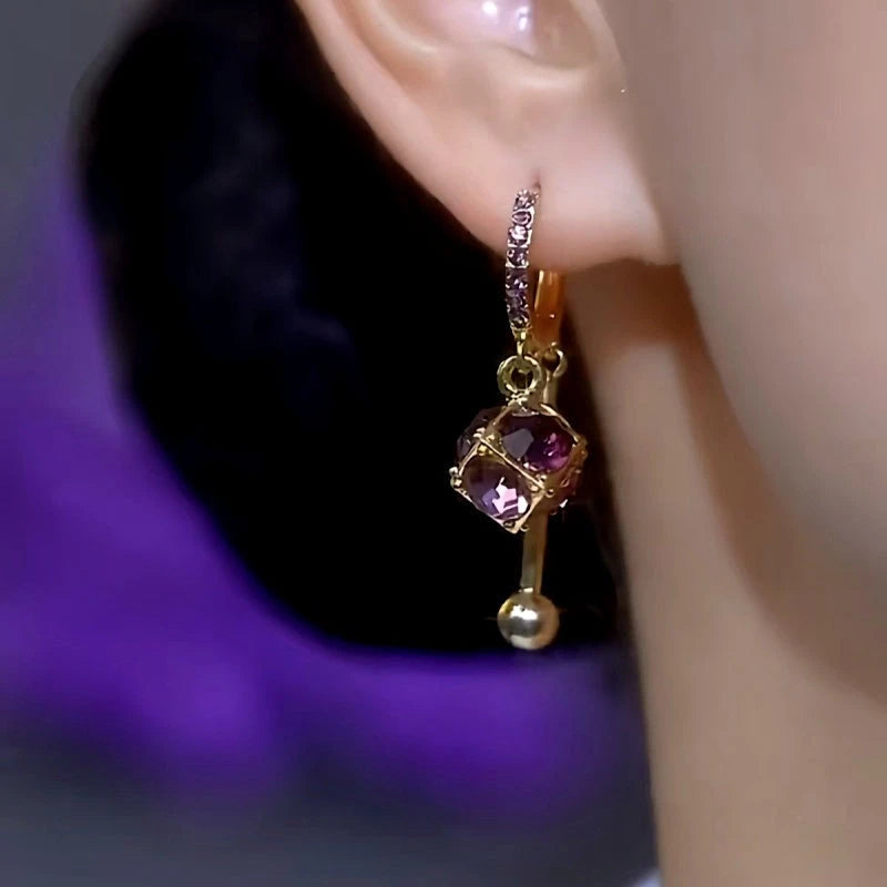Gold purple cubic crystal dangle huggie hoop earring worn on ear, side view