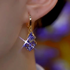 Gold purple crystal double rhombus drop earring on ear, angled close up