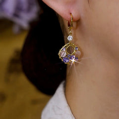 Side view of vintage gold purple crystal cat's eye dangle hoop earring on ear