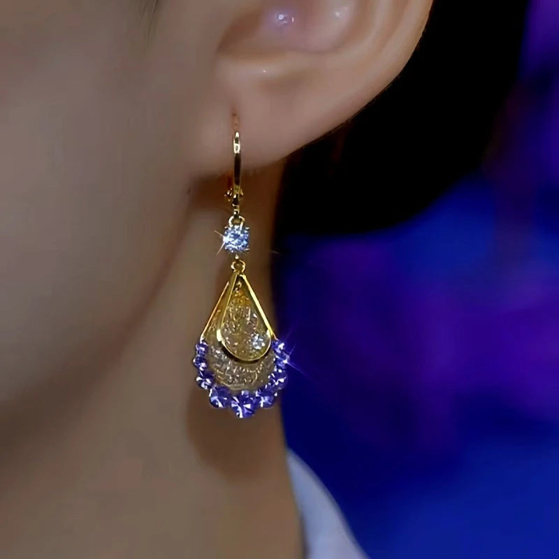 Gold purple crystal teardrop dangle earring on female ear, front angle close-up