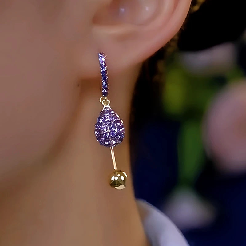 Purple crystal teardrop gold ball drop hoop earring worn on ear