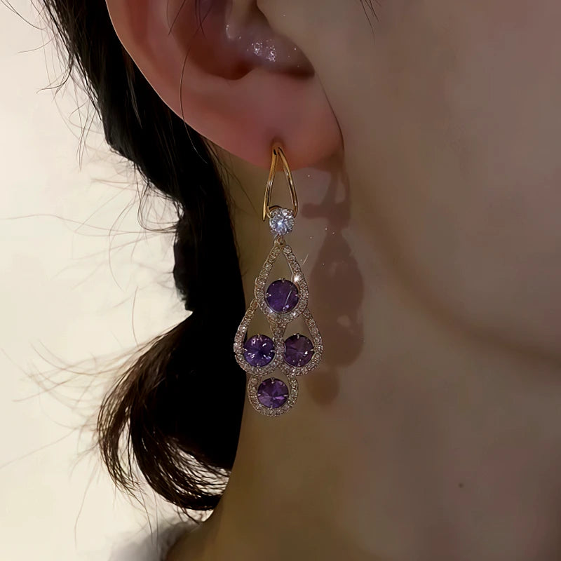 Purple crystal gold drop dangle earring worn on woman's ear
