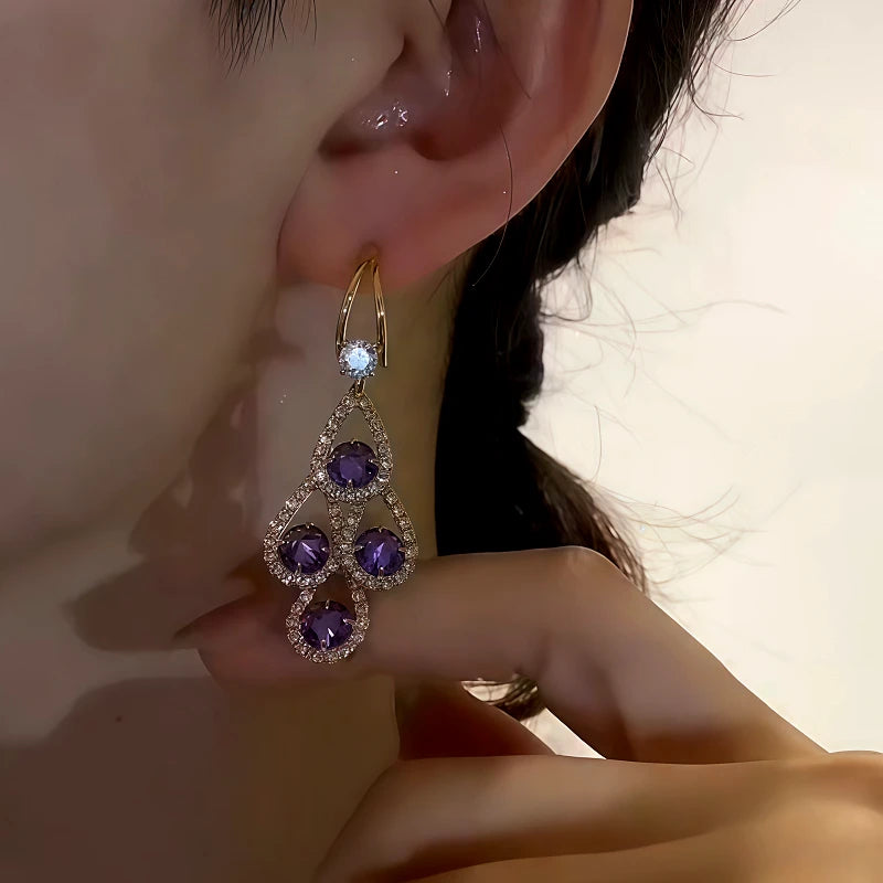 Close-up of purple crystal gold dangle earring on female ear