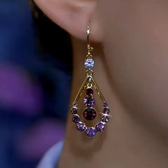 Angled closeup of gold purple crystal teardrop drop earring on ear