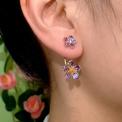 Purple crystal flower ear jacket stud earrings worn on a woman's ear