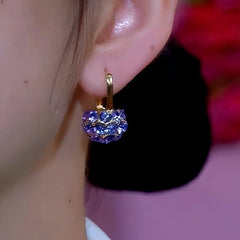 Gold purple crystal drop hoop earring worn on ear, front close-up view