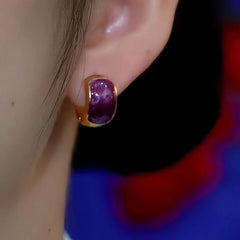 Side view of purple stone gold huggie earring worn on ear