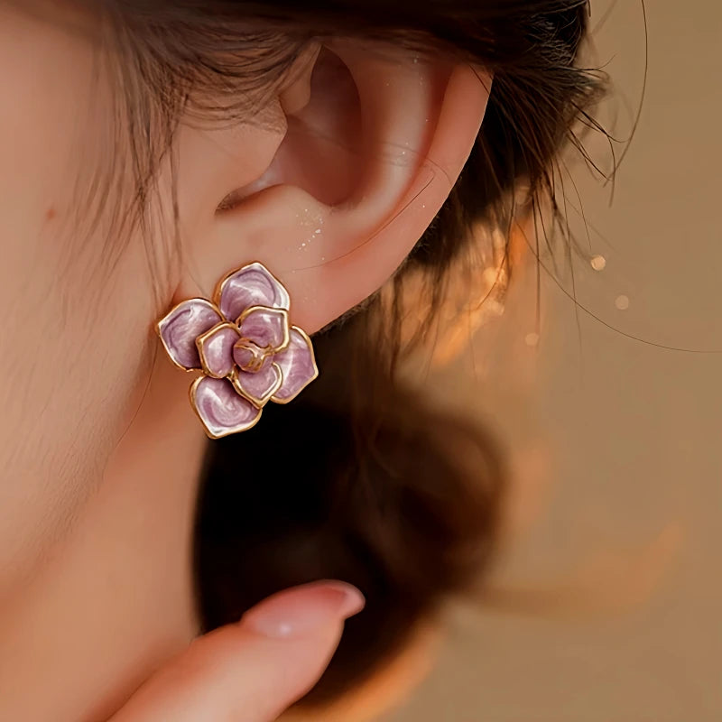 Close-up of purple gold-trimmed enamel flower stud earring on ear