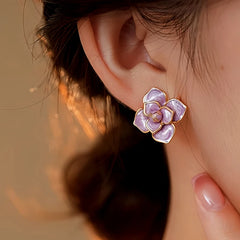 Angled close-up of purple enamel flower stud earring worn on ear
