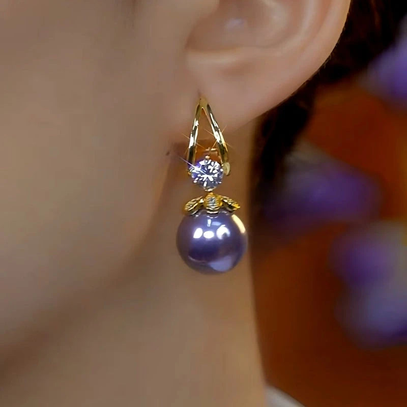 Gold purple pearl crystal drop earring worn on woman's ear, side view