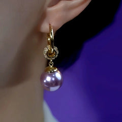 Side view of gold hoop purple pearl drop earring with crystal accent worn on ear