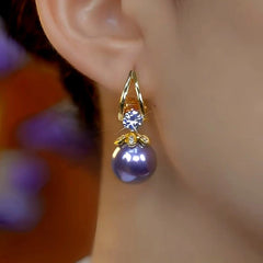 Front closeup of gold purple pearl crystal drop earring on woman's ear