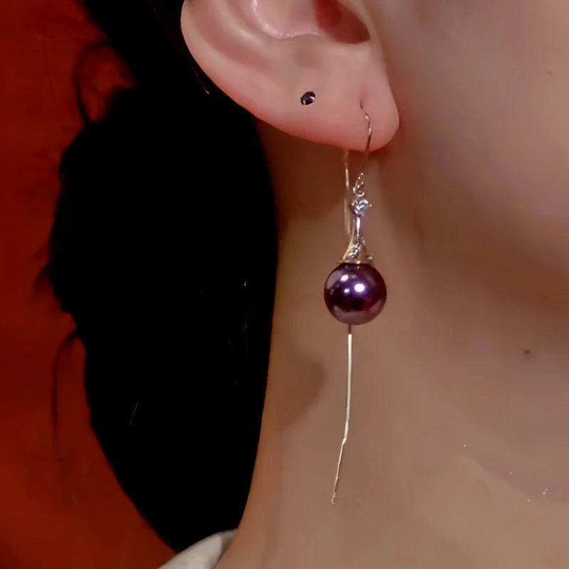 Close-up of women's purple pearl long tassel dangle earring worn on ear