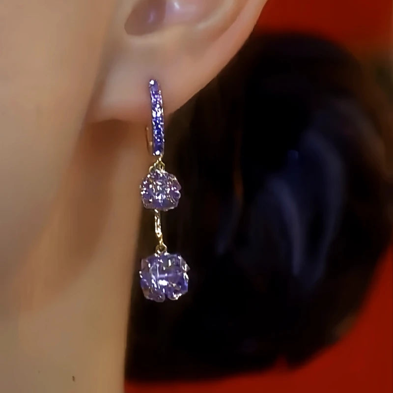 Close-up side view of purple crystal drop hoop earring worn on ear