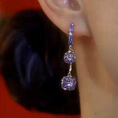 Angled close-up of purple crystal drop hoop earring worn on ear