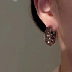 Smoky brown crystal huggie hoop earring worn on left ear close-up